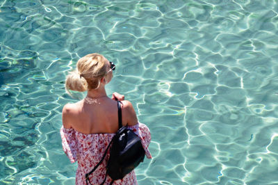 High angle view of woman standing by swimming pool