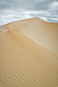 Sand dunes in desert against sky