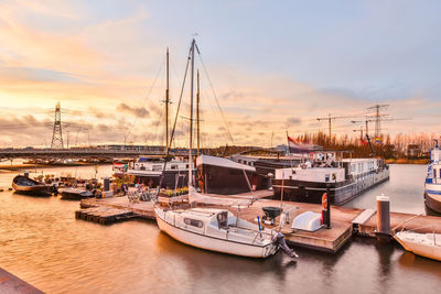 Boats moored at harbor against sky during sunset