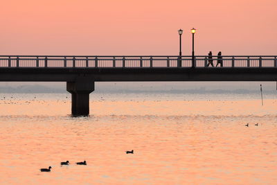 Scenic view of bridge over sea against orange sky