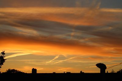 Silhouette landscape against dramatic sky during sunset