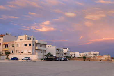 Houses on beach against sky during sunset