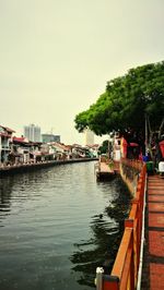 Buildings by river against clear sky