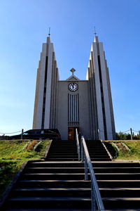 Low angle view of steps amidst buildings against clear blue sky