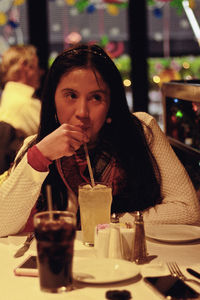 Portrait of a young woman drinking glass at restaurant