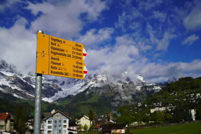 Information sign by buildings in city against sky