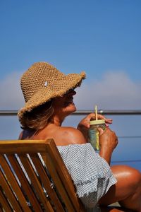 Rear view of woman sitting at beach against clear sky