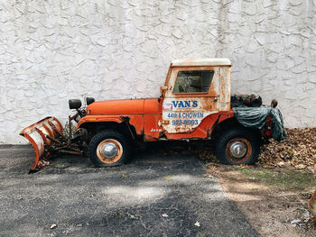 Old vintage car parked on road against wall