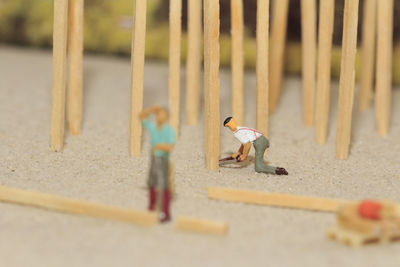Close-up of figurines with matchsticks on sand