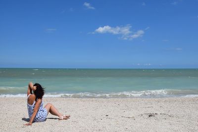 Full length of woman relaxing on beach against sky
