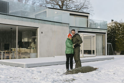 Man and woman standing in front of house at winter