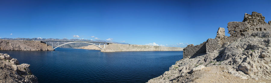 Arch bridge over river against blue sky