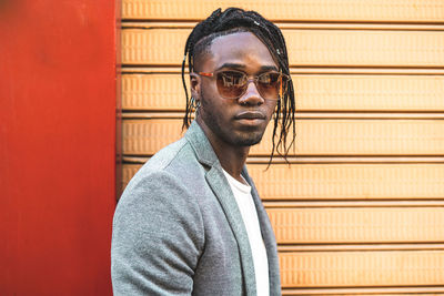 Portrait of young man standing against wall