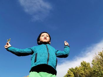 Low angle view of a boy on blue against sky