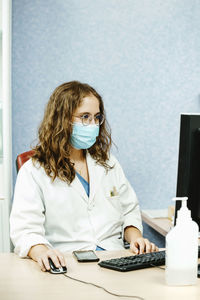 Doctor wearing mask using computer in clinic