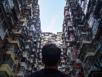 Rear view of man in city against sky