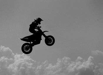 Side view of motocross racer performing mid-air against sky