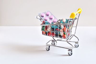 Close-up of pills in shopping cart on white background