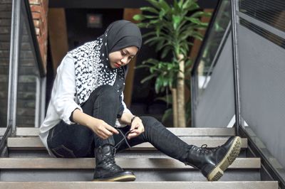 Full length of young woman sitting on seat