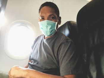 Portrait of man wearing mask sitting in airplane