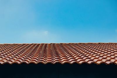 Low angle view of tiled roof against blue sky