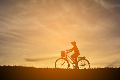 Silhouette bicycle on field against sky during sunset