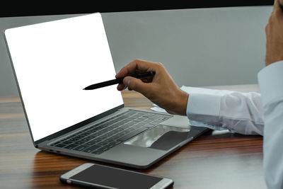 Midsection of man using mobile phone on table