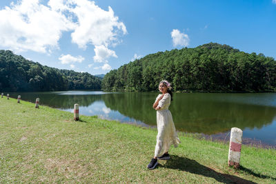 Rear view of woman standing by lake against sky