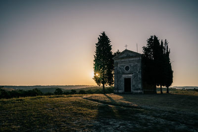 Church on field by building against sky during sunset