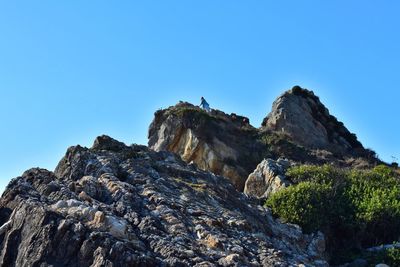 Low angle view of rock formation against clear blue sky