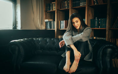 Young woman sitting on sofa at home