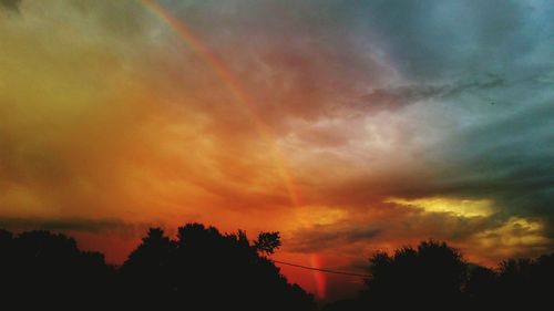 Low angle view of silhouette trees against dramatic sky