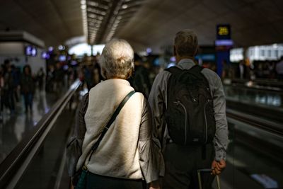 Rear view of people standing on escalator