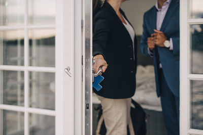 Midsection of mature couple locking glass door at holiday villa