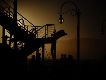 Silhouette friends standing by staircase during sunset