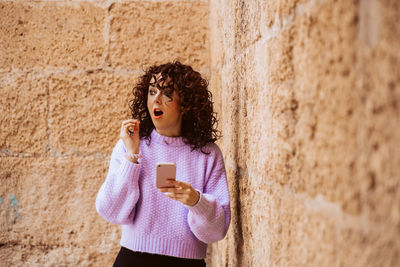 Young woman standing against wall