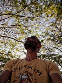 Low angle view of man wearing hat against trees