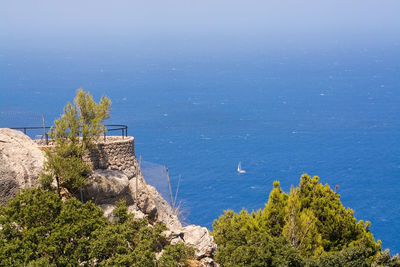 High angle view of trees and sea against blue sky