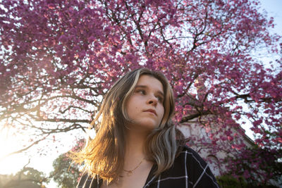 Portrait of beautiful young woman standing against trees