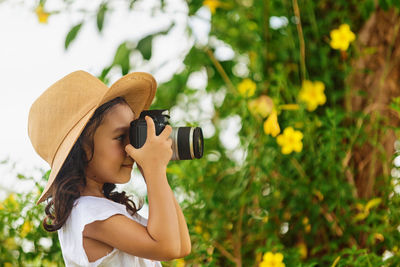 Portrait of boy photographing against plants