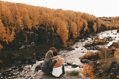 Rear view of men sitting on rock