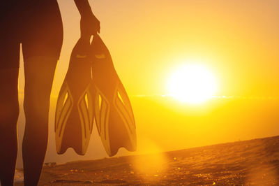 Female diver in a wetsuit holds fins in her hands. enjoying water sports, rear view of a young adult