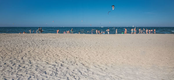 People on beach against blue sky