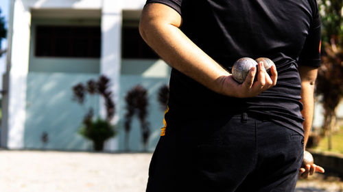 Midsection of man holding sports ball outdoors