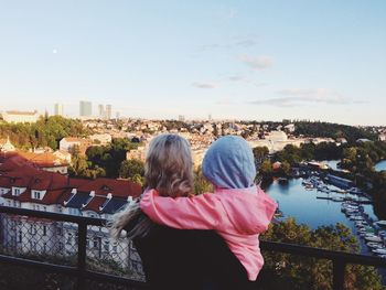 Rear view of mother carrying daughter against cityscape