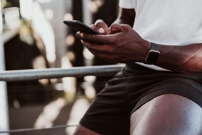 Sportsman using smart phone while sitting