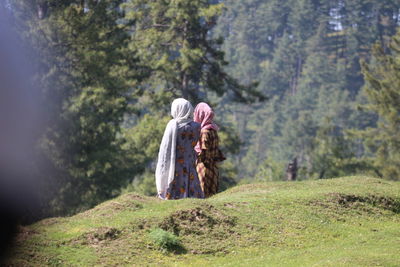 Rear view of people on rock amidst trees