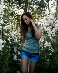 Beautiful young woman standing by flowering plants