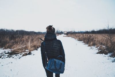 Rear view of woman on snow covered pathway against sky