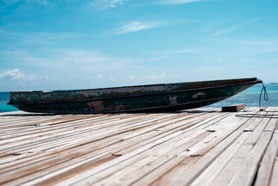 Old wooden boat sitting on the pier against sky.